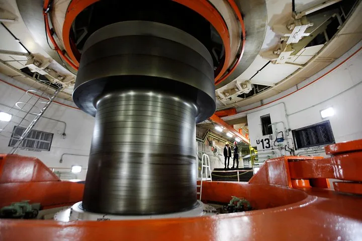 Large industrial machinery spinning inside the powerhouse of a hydroelectric dam.
