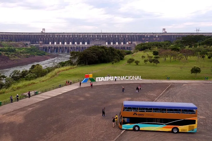 A large dam structure with a parked tour bus in the foreground.