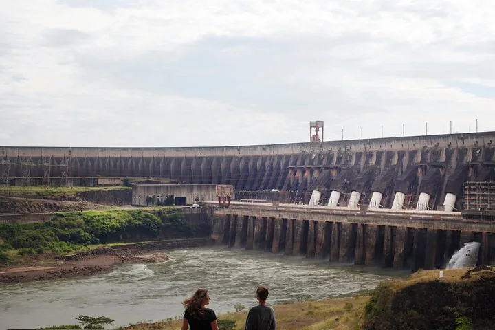 Two people looking at the vast concrete structure of Itaipu Dam.