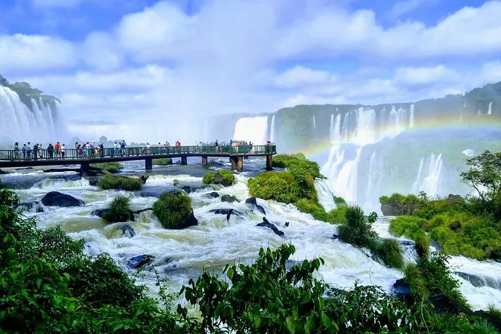 A stunning rainbow arches over a wide span of powerful waterfalls.